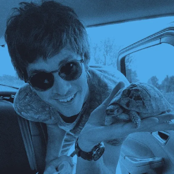 Greg Kemp in sunglasses, holding a small tortoise