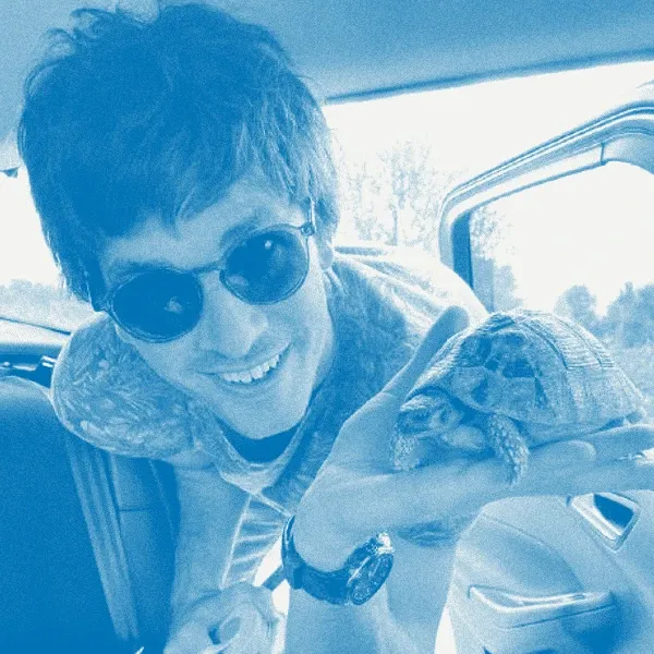 Greg Kemp in sunglasses, holding a small tortoise